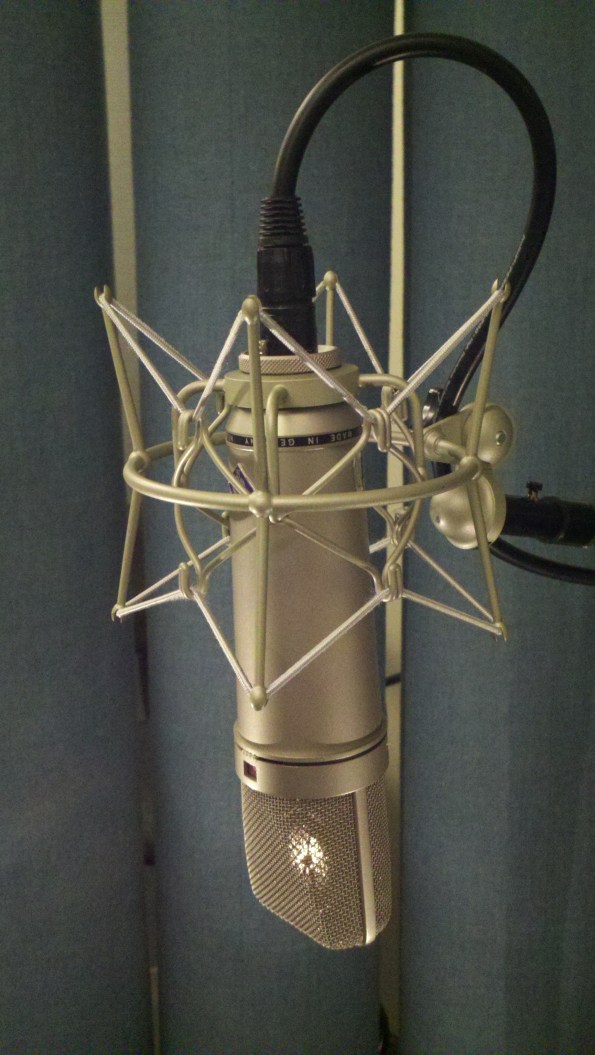 Neumann u87 condenser microphone profile view with mic element reflection and spider shockmount